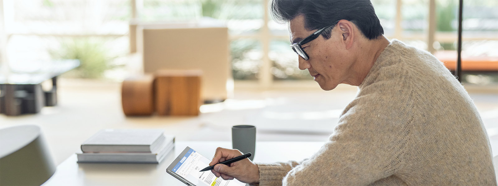 رجل يجلس على الطاولة ويستخدم قلم Surface على جهاز Surface الخاص به