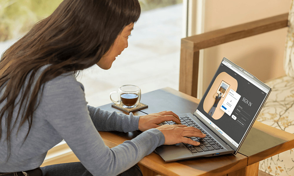 A person leaning over a coffee table, looking at an open laptop