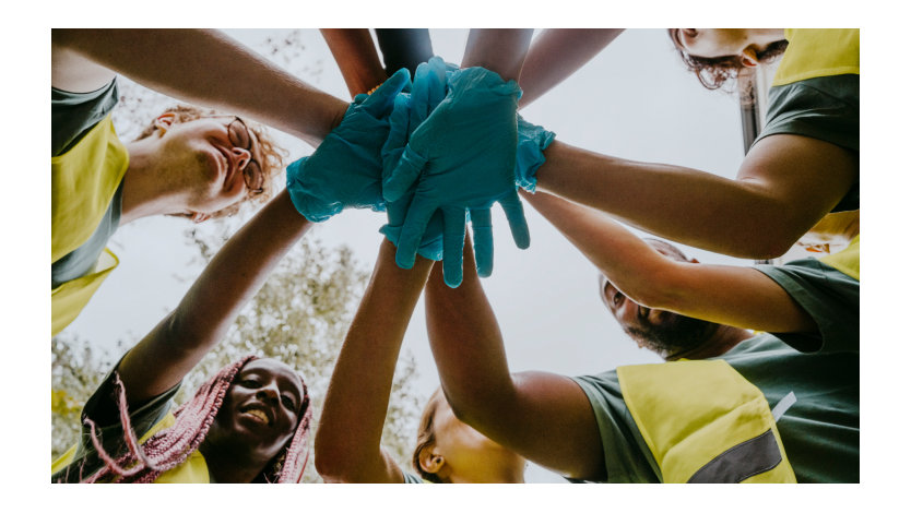 Un groupe de bénévoles se réunit en cercle, unissant leurs mains dans un geste symbolique de solidarité.