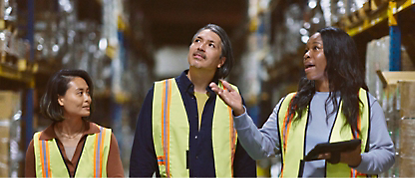 Three women in vests standing in a warehouse