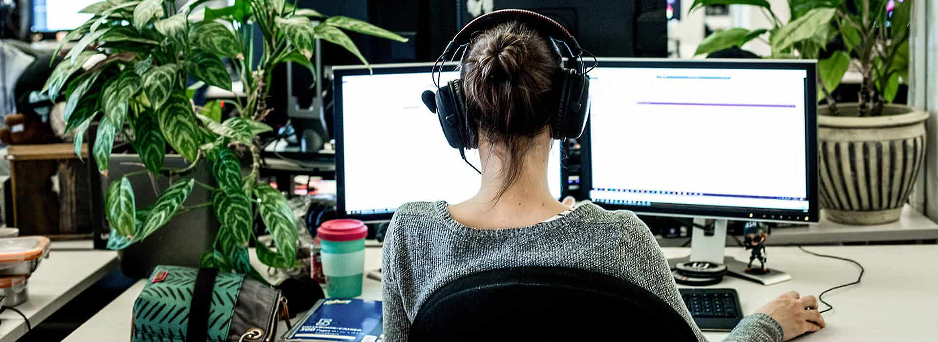 A person wearing over-the-ear headphones and working at their desk 
