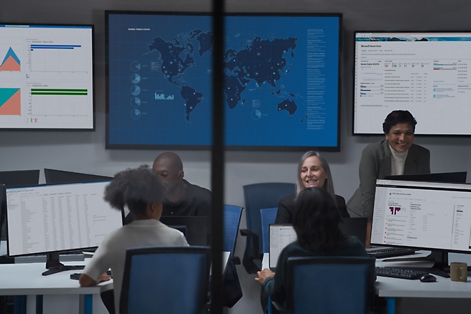People discussing with multiple desktops open and opened graph chart, world map in big screen board